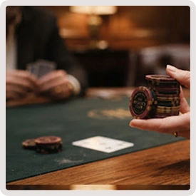 Dichtbij van een hand die een stapel pokerfiches vasthoudt aan een speeltafel in een sfeervol casino.